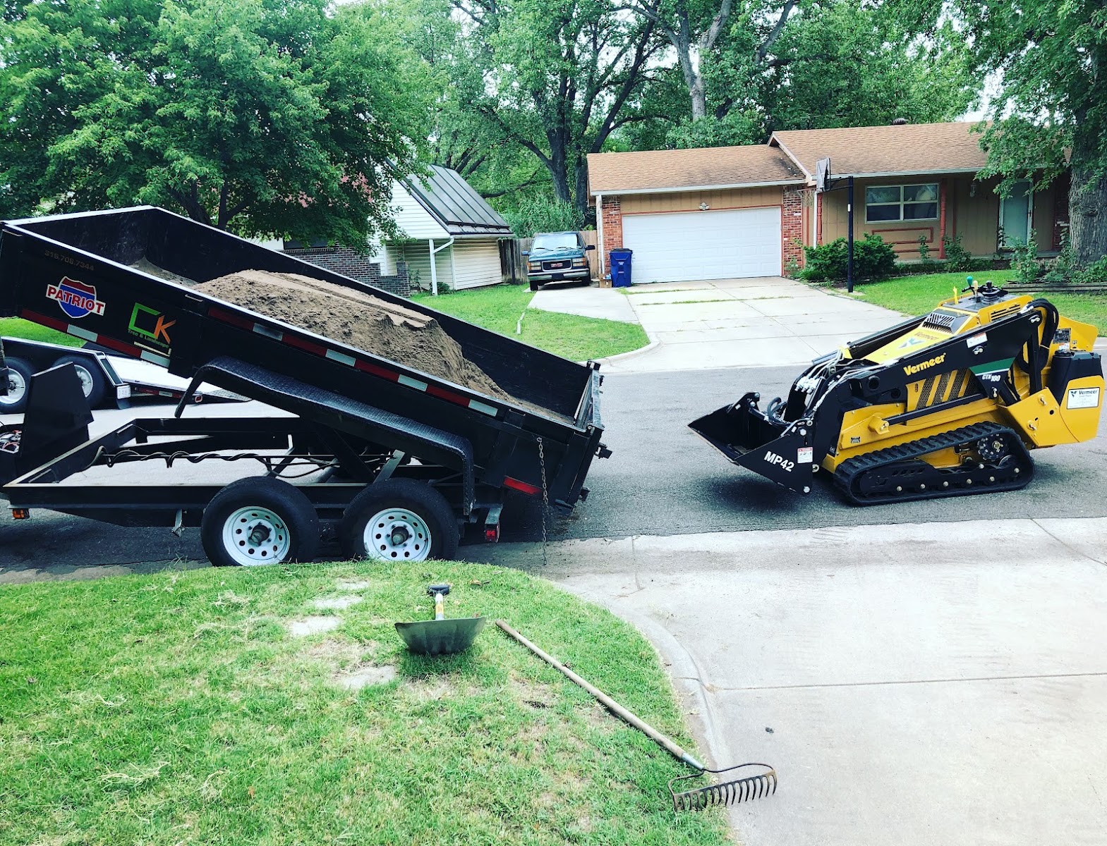 The C.K. dump trailer tipping a load of material with a compact skid loader alongside